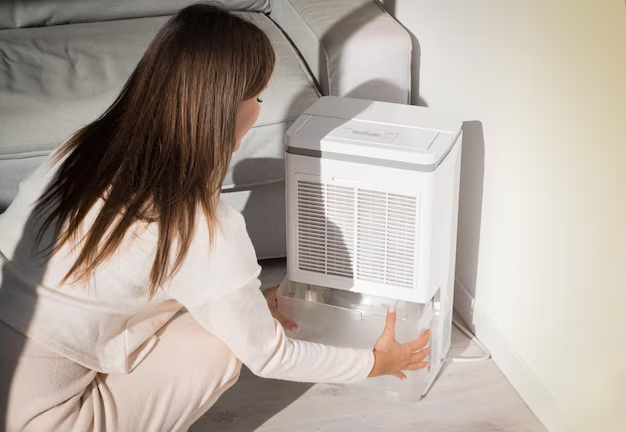Woman removing water container from a dehumidifier.