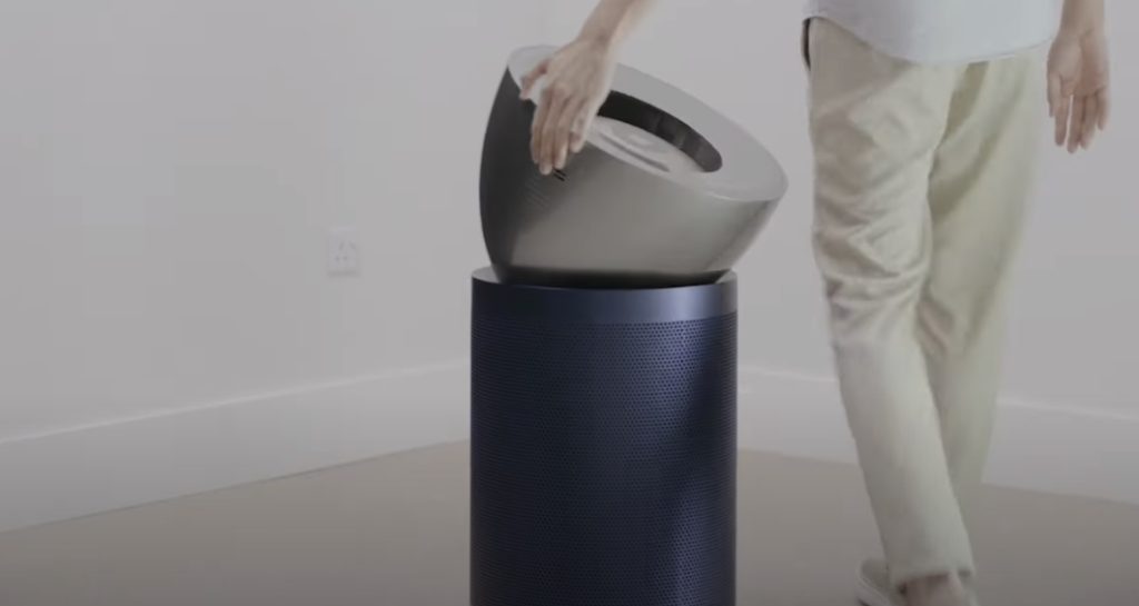 Person next to a Dyson air purifier, touching it.
